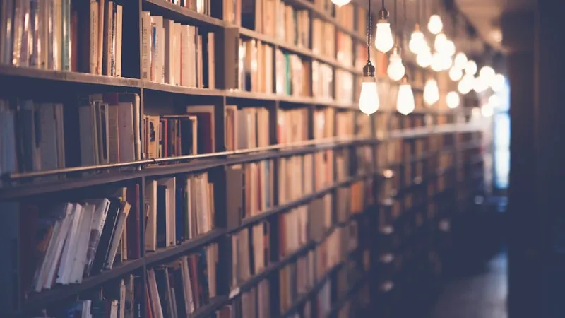 Library aisle with hanging lightbulbs — the best way to learn French verbs
