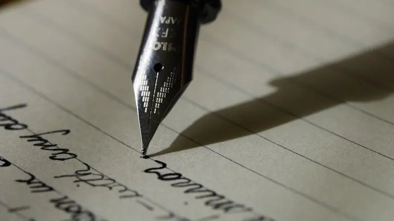 Close-up of a fountain pen writing in cursive on lined paper — practicing French conjugation