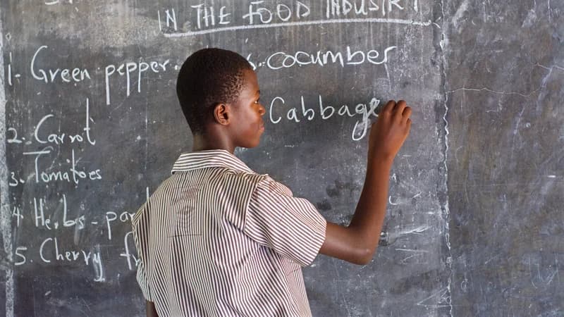 Student writing a vocabulary list on a chalkboard — a complete guide to the French passé composé