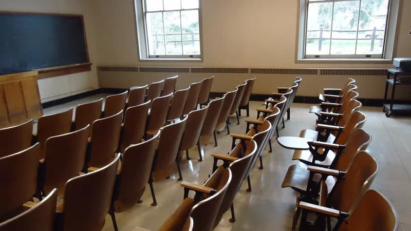 Empty classroom with rows of desks facing a blackboard — learning the rules of the French present tense